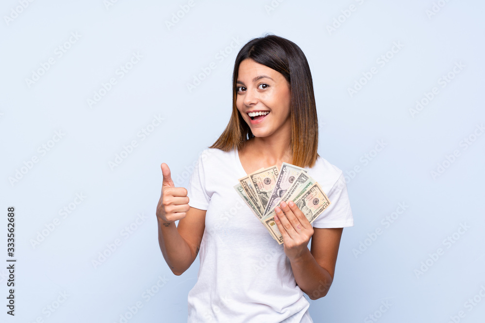 Young woman over isolated blue background taking a lot of money Young woman over isolated blue background taking a lot of money