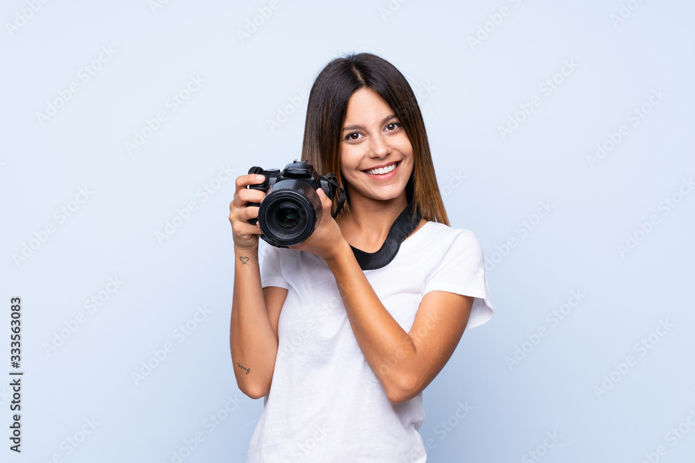 Young woman over isolated blue background with a professional camera Young woman over isolated blue background with a professional camera