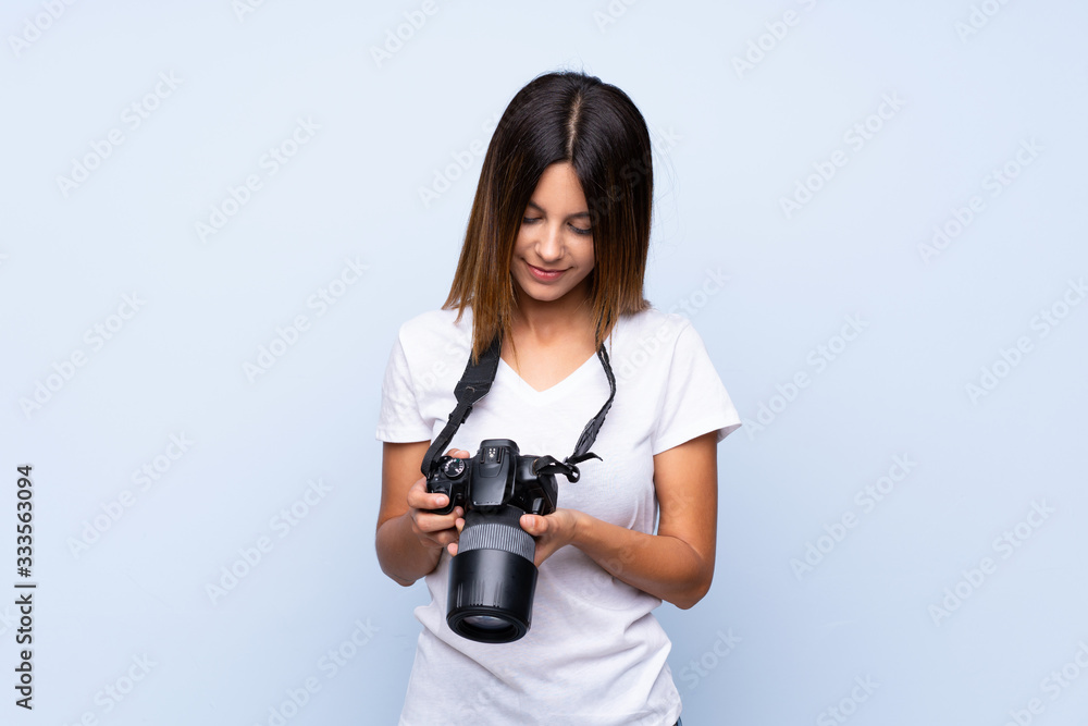 Young woman over isolated blue background with a professional camera Young woman over isolated blue background with a professional camera