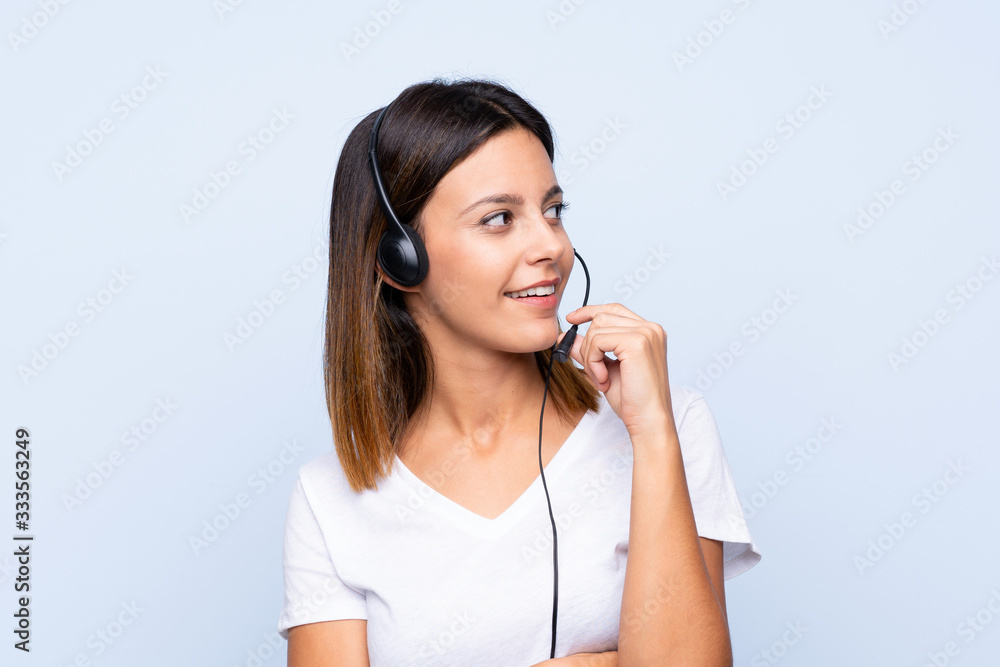 Young woman over isolated blue background working with headset Young woman over isolated blue background working with headset