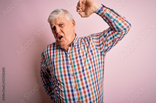 Senior handsome hoary man wearing casual colorful shirt over isolated pink background stretching back, tired and relaxed, sleepy and yawning for early morning