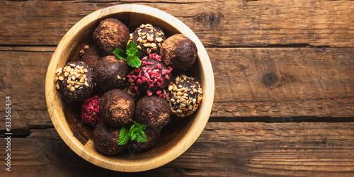 Various Homemade Raw Vegan Truffles or Energy Balls  such as Almond and Cacao  Dark Chocolate and Hazelnut Butter inside wooden Plate and Rustic Background  banner size