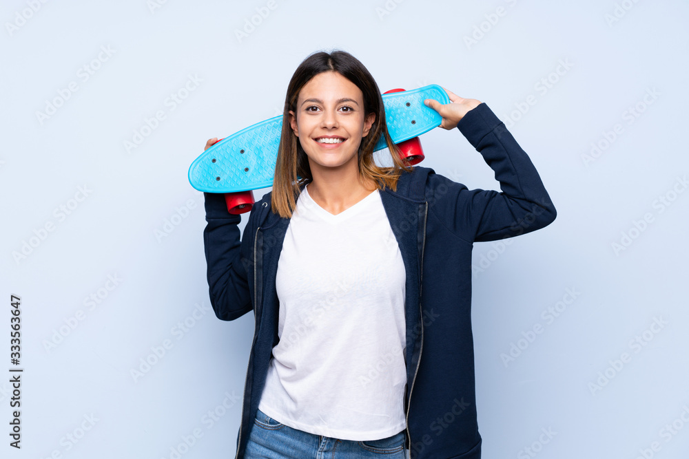 Young woman over isolated blue background with skate Young woman over isolated blue background with skate