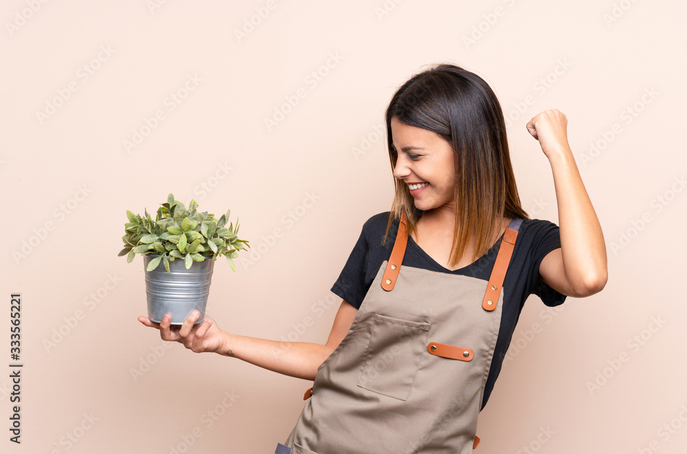 Young woman holding a plant celebrating a victory Young woman holding a plant celebrating a victory