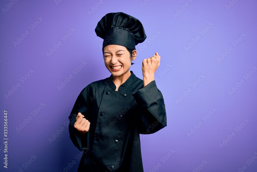 Young beautiful chinese chef woman wearing cooker uniform and hat over purple background celebrating surprised and amazed for success with arms raised and eyes closed. Winner concept. Young beautiful chinese chef woman wearing cooker uniform and hat over purple background celebrating surprised and amazed for success with arms raised and eyes closed. Winner concept.