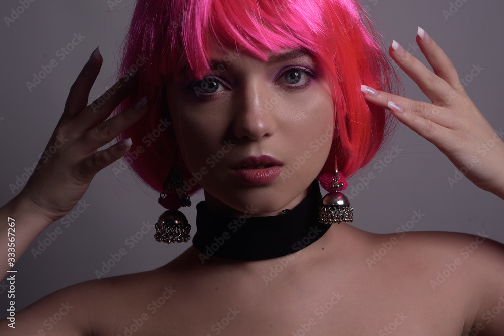 Fototapeta premium Portrait of a girl with pink hair and chic, fashionable earrings, pink earrings with silver. Jewelry, accessories. Stylish girl in a checker and means. Girl with pink make-up. Professional makeup.
