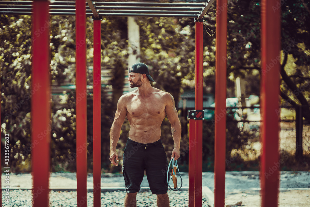 Obraz premium Bearded bodybuilder man exercising on monkey bars for the upper-body in a modern calisthenics park outdoors on a sunny day.