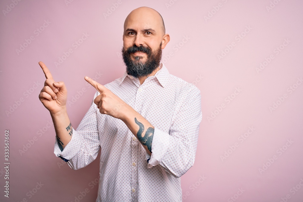 Handsome bald man with beard wearing elegant shirt over isolated pink background smiling and looking at the camera pointing with two hands and fingers to the side. Handsome bald man with beard wearing elegant shirt over isolated pink background smiling and looking at the camera pointing with two hands and fingers to the side.