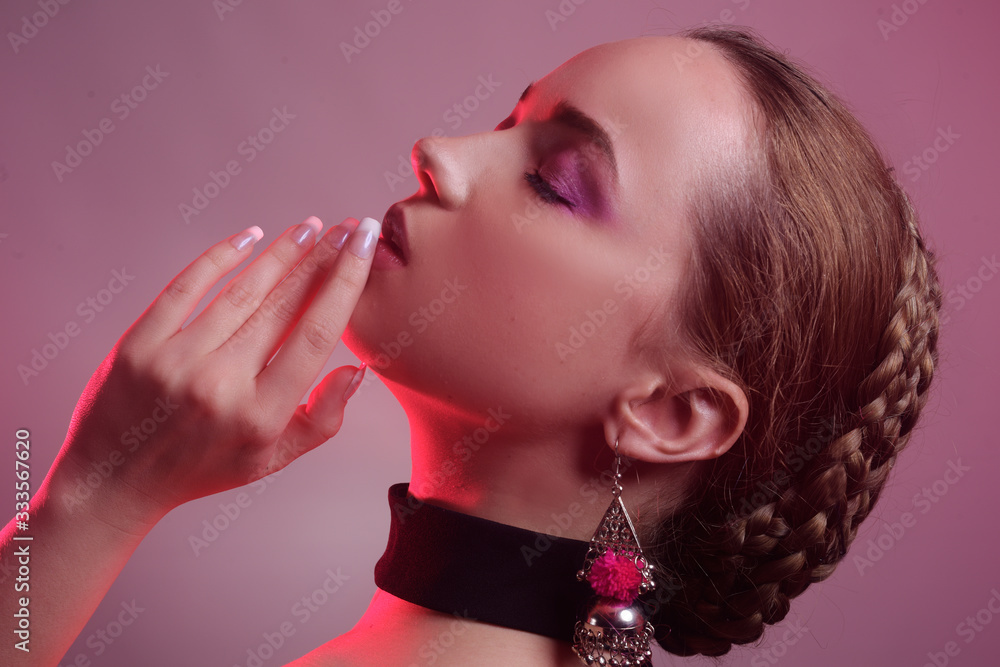 Obraz premium Natural girl in accessories. Girl with a beautiful professional braid hairstyle. Girl on a pink background with beautiful daily pink make-up. An interesting image. 
