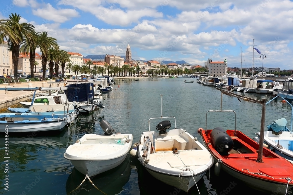 Small colorful fishing boats in the port of Split, Croatia. Traditional Mediterranean architecture with landmark Saint Domnius tower in the background. 