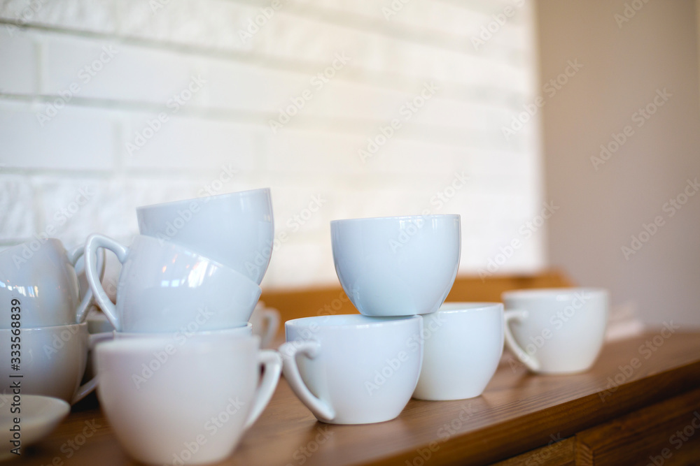 Set of small, white coffee mugs on a wooden tabletop in a cafe. Set of small, white coffee mugs on a wooden tabletop in a cafe.