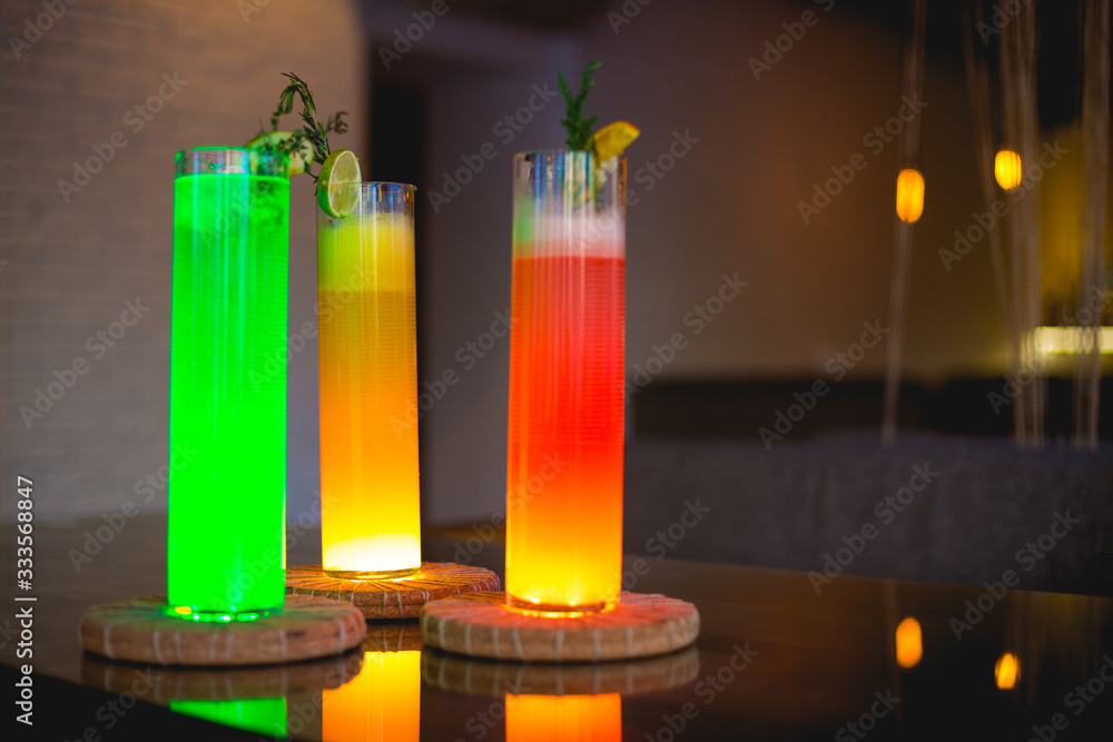 Cocktails in tall glasses with a backlight on a tray stand in a bar on the table. Cocktails in tall glasses with a backlight on a tray stand in a bar on the table.