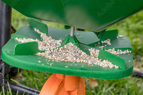Fotografie Closeup of lawn fertilizer spreader with granules of weed killer herbicide, urea