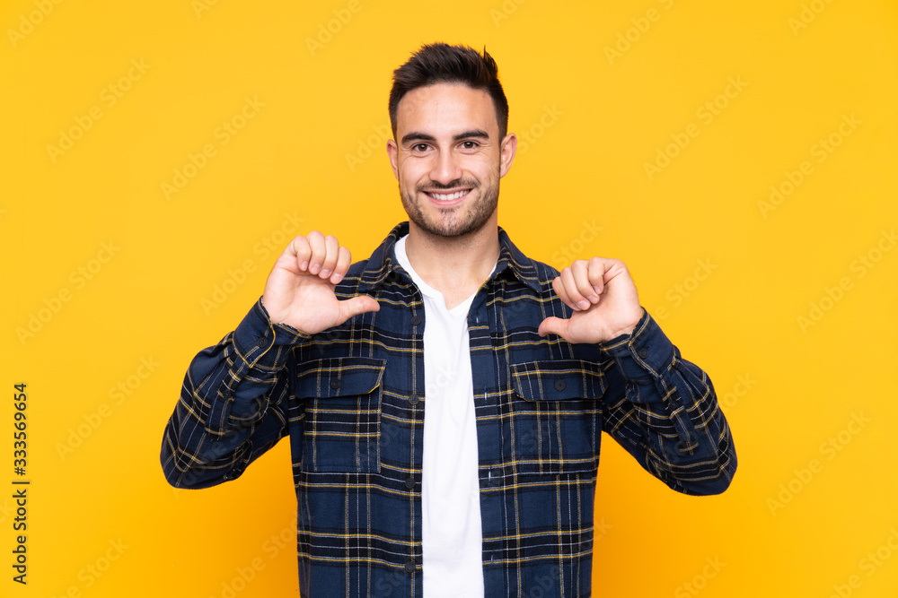 Young handsome man over isolated yellow background proud and self-satisfied Young handsome man over isolated yellow background proud and self-satisfied