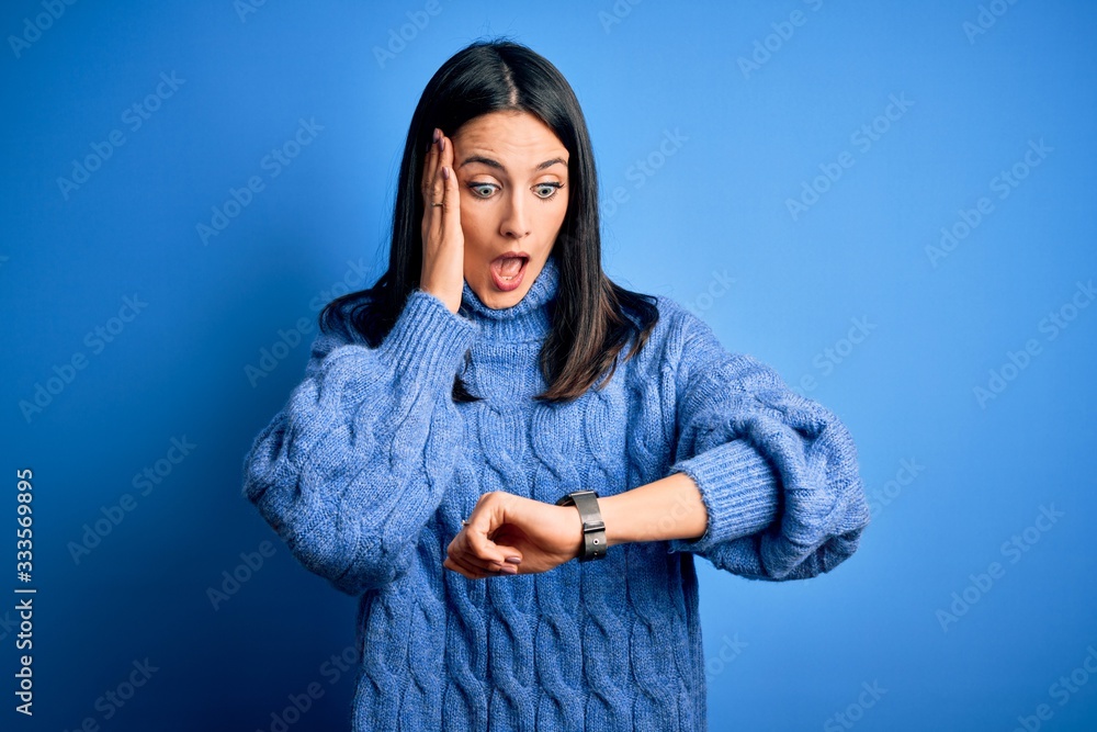 Young brunette woman with blue eyes wearing casual turtleneck sweater Looking at the watch time worried, afraid of getting late Young brunette woman with blue eyes wearing casual turtleneck sweater Looking at the watch time worried, afraid of getting late