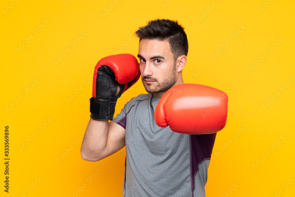 Sport man over isolated yellow wall with boxing gloves