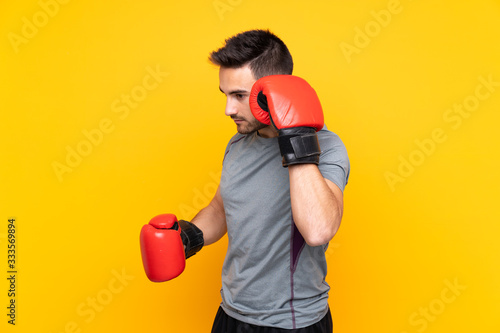 Sport man over isolated yellow wall with boxing gloves © luismolinero