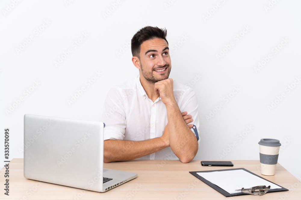 Young business man with a mobile phone in a workplace laughing and looking up Young business man with a mobile phone in a workplace laughing and looking up