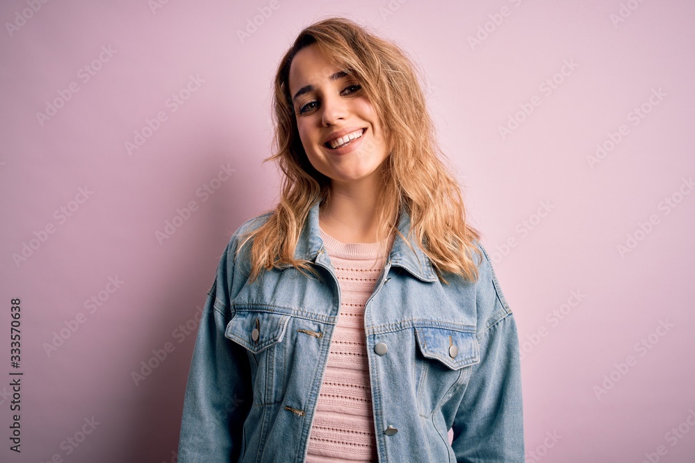 Young beautiful blonde woman wearing casual denim jacket standing over pink background with a happy and cool smile on face. Lucky person. Young beautiful blonde woman wearing casual denim jacket standing over pink background with a happy and cool smile on face. Lucky person.