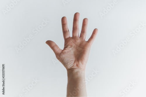 Palma da mão aberta de mulher branca, mostrando os 5 dedos