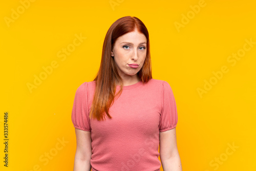 Young redhead woman over isolated yellow background sad