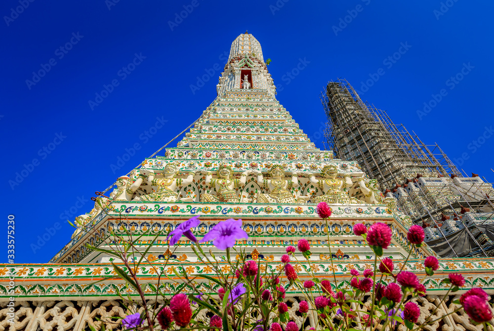 Wat Arun, temple of the dawn with blue sky and flowers
