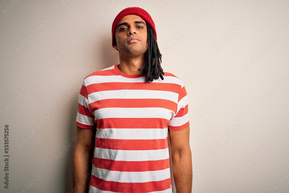 Fototapeta premium Young handsome african american man with dreadlocks wearing striped t-shirt and wool hat Relaxed with serious expression on face. Simple and natural looking at the camera.