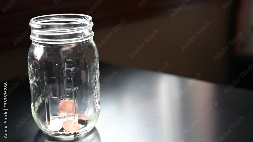 Slow motion of dropping coins into a glass jar Slow motion of dropping coins into a glass jar