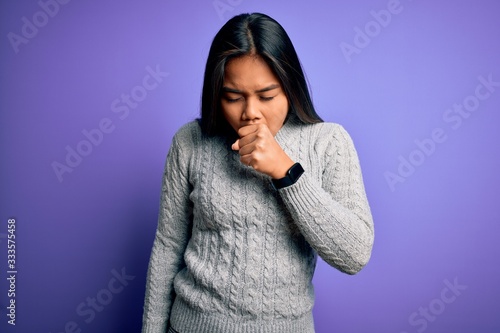 Young beautiful asian girl wearing casual sweater standing over isolated purple background feeling unwell and coughing as symptom for cold or bronchitis. Health care concept. © Krakenimages.com