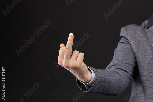 A man in a jacket shows a fuck you with his hand on a black background.