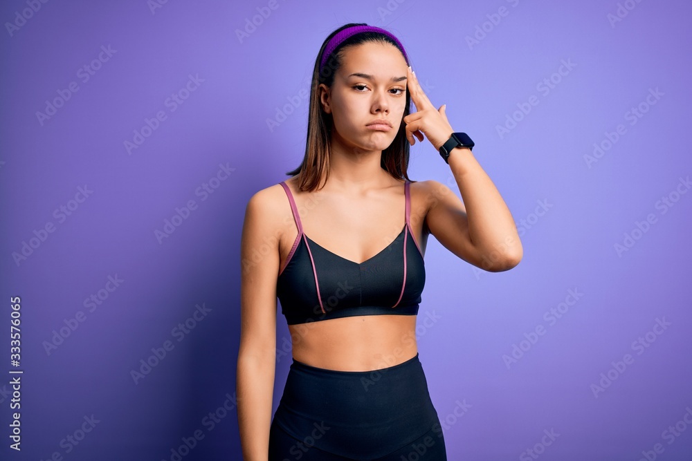 Young beautiful sporty girl doing sport wearing sportswear over isolated purple background Shooting and killing oneself pointing hand and fingers to head like gun, suicide gesture. Young beautiful sporty girl doing sport wearing sportswear over isolated purple background Shooting and killing oneself pointing hand and fingers to head like gun, suicide gesture.