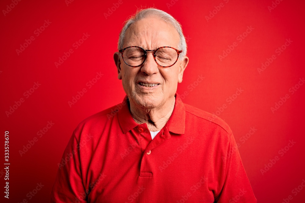Grey haired senior man wearing glasses and casual t-shirt over red background with hand on stomach because indigestion, painful illness feeling unwell. Ache concept. Grey haired senior man wearing glasses and casual t-shirt over red background with hand on stomach because indigestion, painful illness feeling unwell. Ache concept.