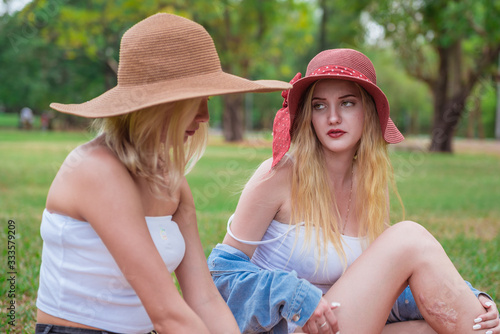 Two young beautiful women talking and chatting in the park © calcassa