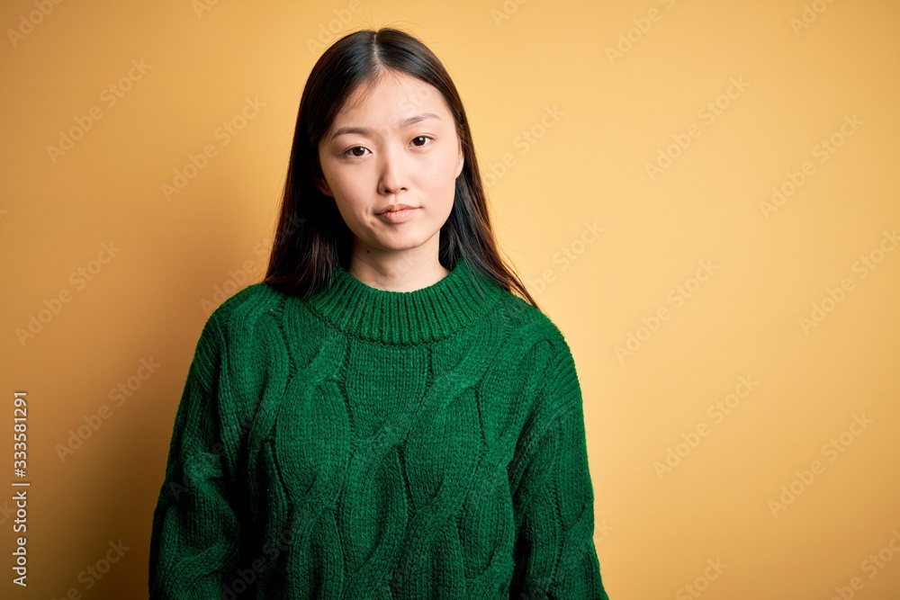 Young beautiful asian woman wearing green winter sweater over yellow isolated background looking sleepy and tired, exhausted for fatigue and hangover, lazy eyes in the morning. Young beautiful asian woman wearing green winter sweater over yellow isolated background looking sleepy and tired, exhausted for fatigue and hangover, lazy eyes in the morning.