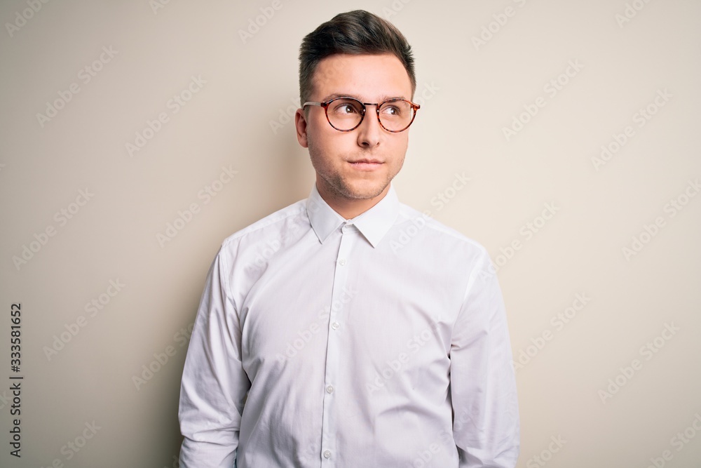Young handsome business mas wearing glasses and elegant shirt over isolated background smiling looking to the side and staring away thinking. Young handsome business mas wearing glasses and elegant shirt over isolated background smiling looking to the side and staring away thinking.
