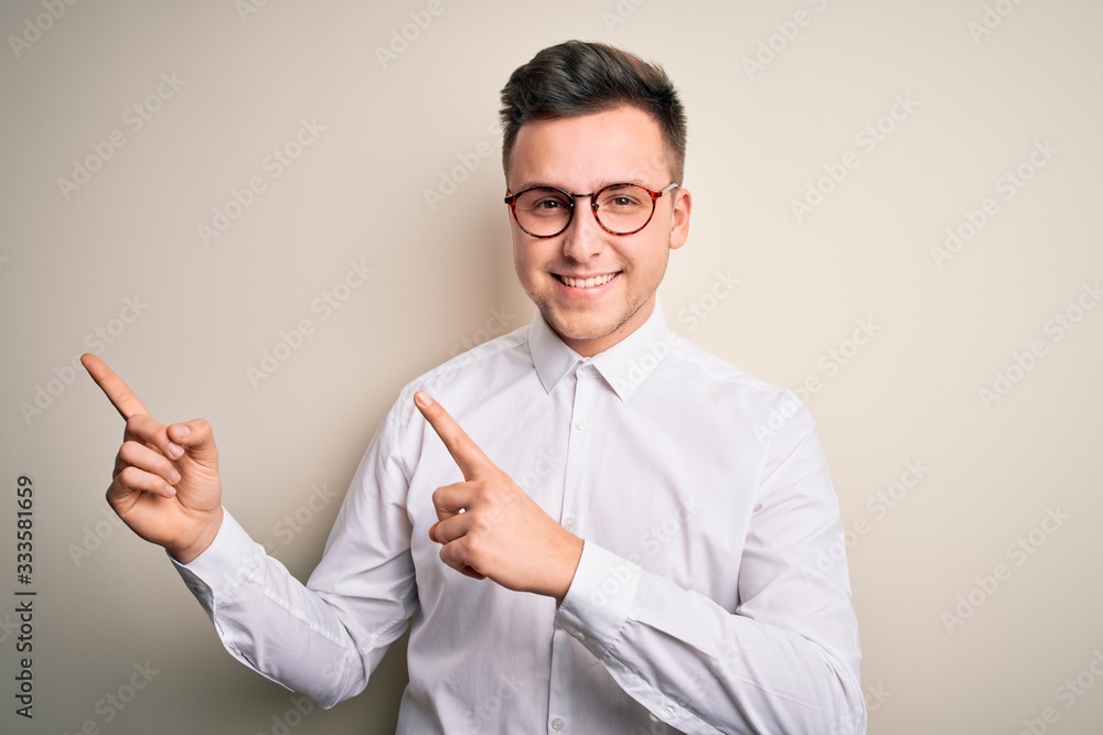 Young handsome business mas wearing glasses and elegant shirt over isolated background smiling and looking at the camera pointing with two hands and fingers to the side. Young handsome business mas wearing glasses and elegant shirt over isolated background smiling and looking at the camera pointing with two hands and fingers to the side.