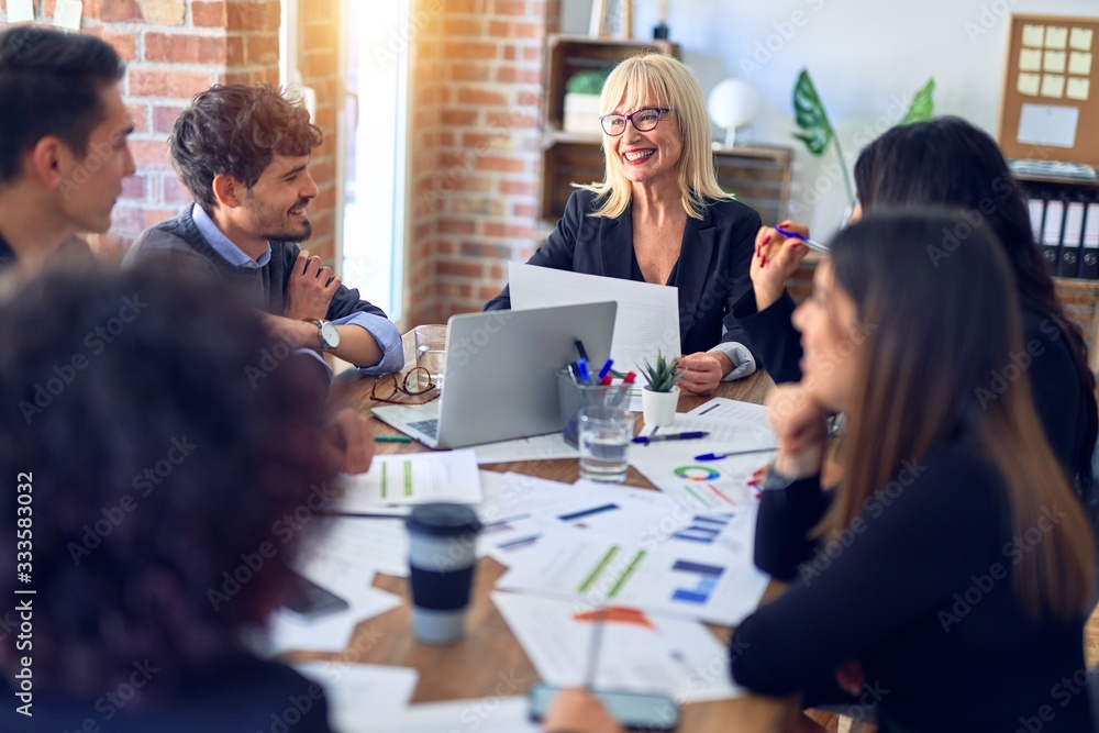 Group of business workers smiling happy and confident. Working together with smile on face using laptop and speaking at the office Group of business workers smiling happy and confident. Working together with smile on face using laptop and speaking at the office