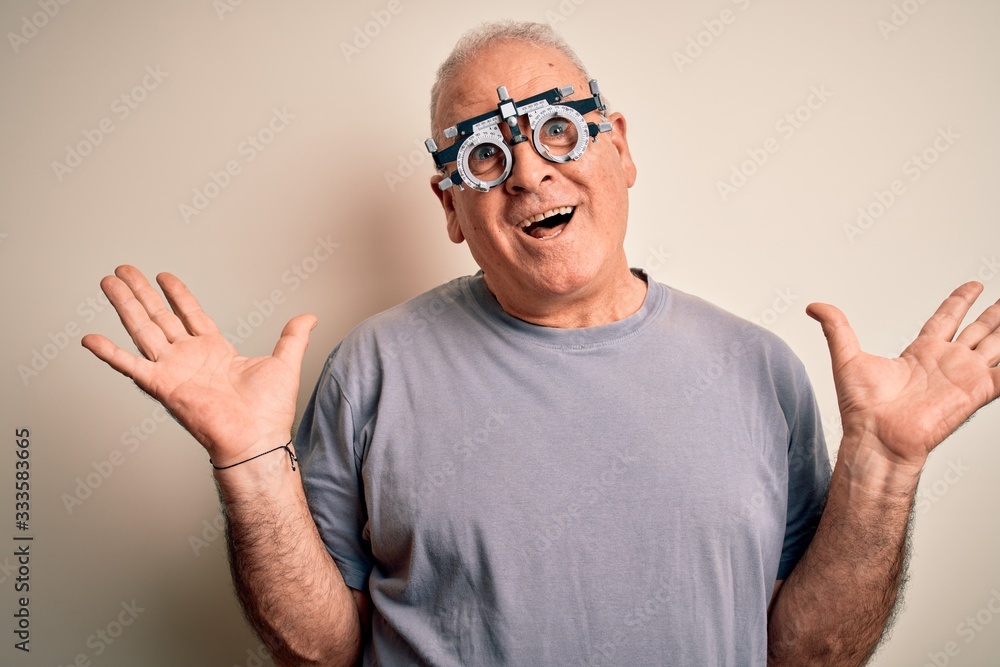 Naklejka premium Middle age hoary man controlling vision wearing optometry glasses over white background celebrating crazy and amazed for success with arms raised and open eyes screaming excited. Winner concept
