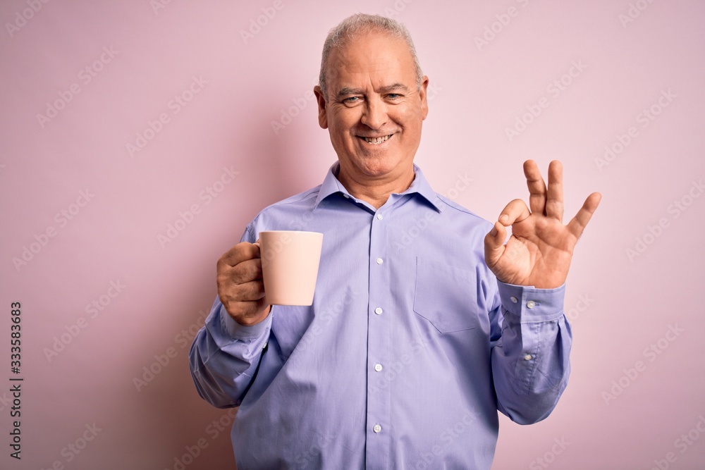 Middle age handsome hoary man drinking mug of coffee over isolated pink background doing ok sign with fingers, excellent symbol Middle age handsome hoary man drinking mug of coffee over isolated pink background doing ok sign with fingers, excellent symbol