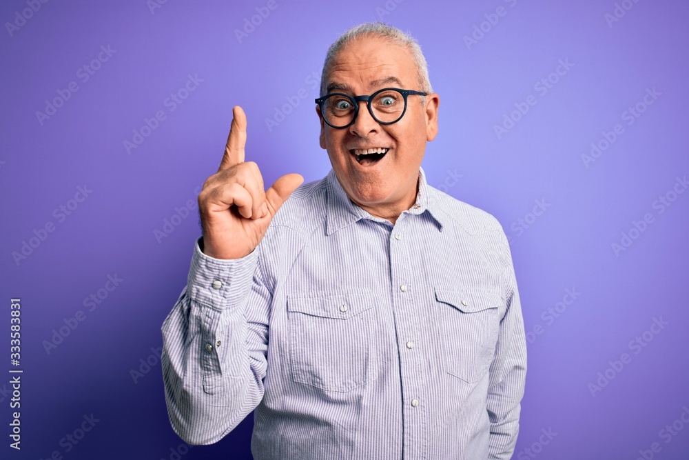 Middle age handsome hoary man wearing striped shirt and glasses over purple background pointing finger up with successful idea. Exited and happy. Number one. Middle age handsome hoary man wearing striped shirt and glasses over purple background pointing finger up with successful idea. Exited and happy. Number one.