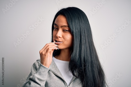 Young beautiful woman standing whasing tooth using toothbrush over isolated white background