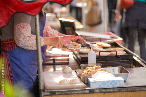 a street food seller is putting minced pork in a dough making fired dumpling