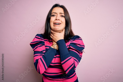 Young brunette elegant woman wearing striped shirt over pink isolated background shouting and suffocate because painful strangle. Health problem. Asphyxiate and suicide concept.