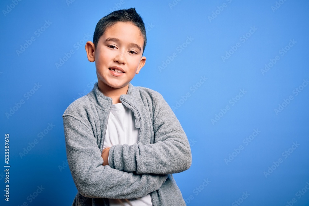 Young little boy kid wearing sport sweatshirt over blue isolated background happy face smiling with crossed arms looking at the camera. Positive person. Young little boy kid wearing sport sweatshirt over blue isolated background happy face smiling with crossed arms looking at the camera. Positive person.