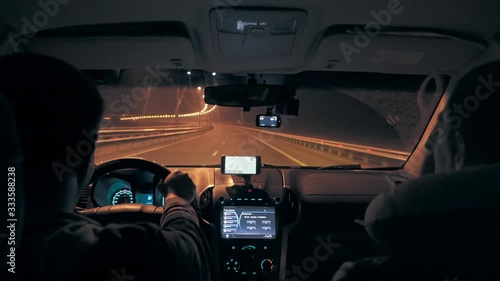 The driver and passenger ride in the car on the night highway