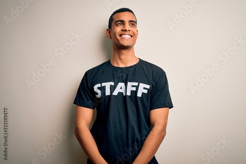 Young handsome african american worker man wearing staff uniform over white background smiling looking to the side and staring away thinking.