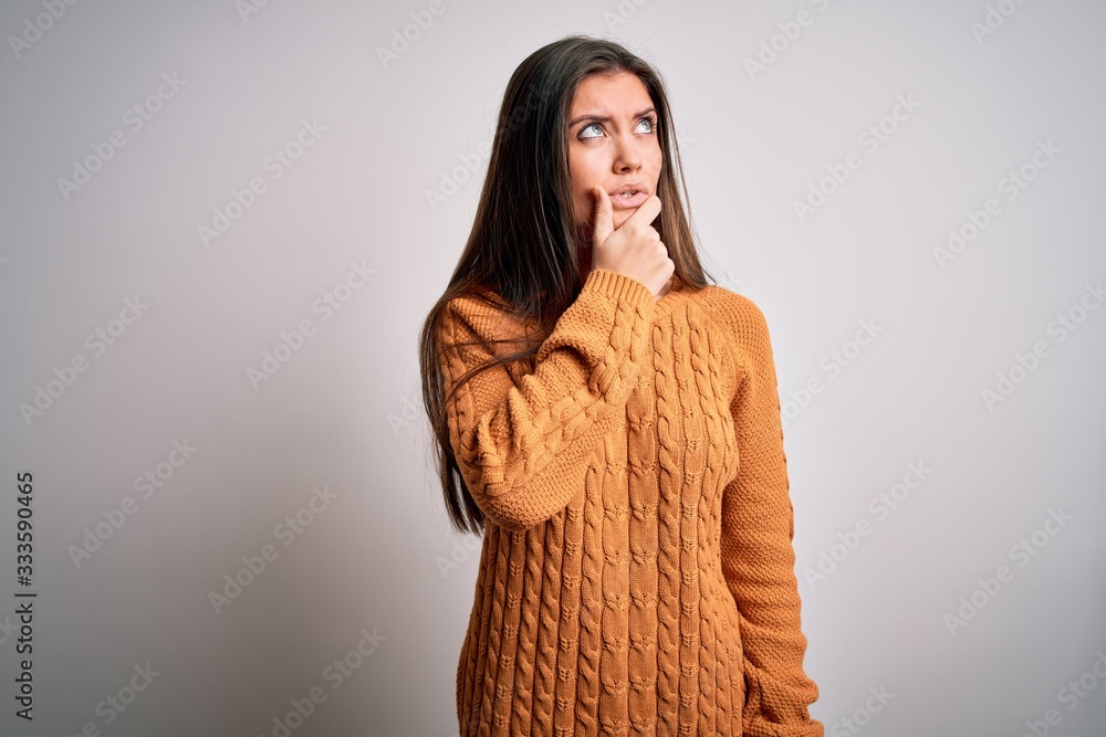 Young beautiful woman with blue eyes wearing casual sweater standing over white background Thinking worried about a question, concerned and nervous with hand on chin Young beautiful woman with blue eyes wearing casual sweater standing over white background Thinking worried about a question, concerned and nervous with hand on chin