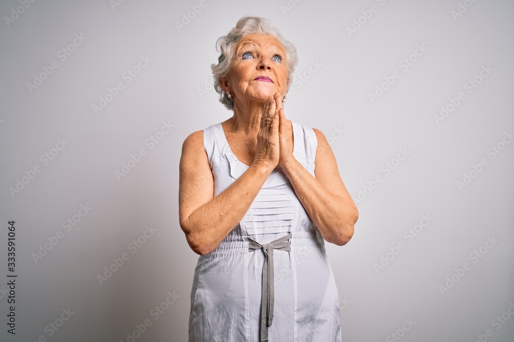 Senior beautiful grey-haired woman wearing casual summer dress over white background begging and praying with hands together with hope expression on face very emotional and worried. Begging.