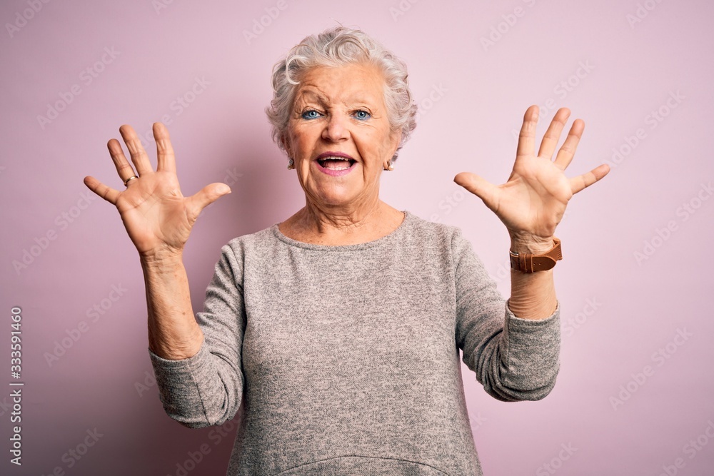 Senior beautiful woman wearing casual t-shirt standing over isolated pink background showing and pointing up with fingers number ten while smiling confident and happy. Senior beautiful woman wearing casual t-shirt standing over isolated pink background showing and pointing up with fingers number ten while smiling confident and happy.