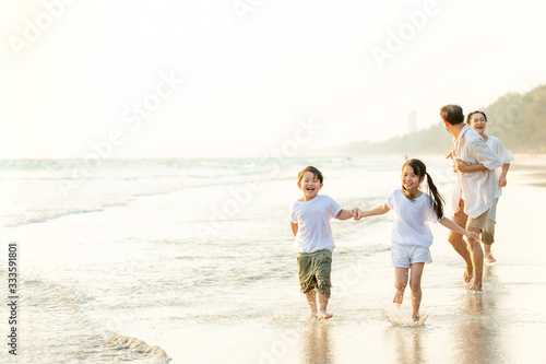 Happy Asian family grandparents with grandchild running and having fun together on the beach in summertime. Grandpa and grandma with kids relax and enjoy summer lifestyle travel holiday vacation.
